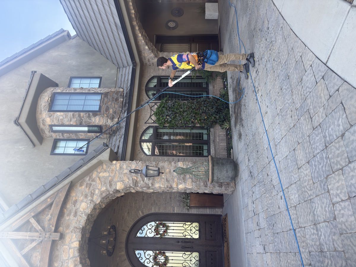 A Window Blasters technician cleaning second-story windows with a pure-water pole